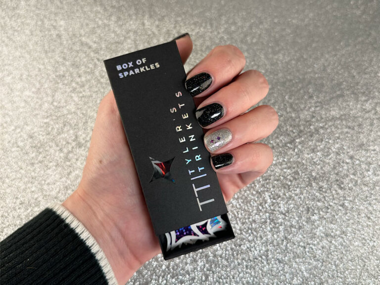 manicured hand holding box of stickers