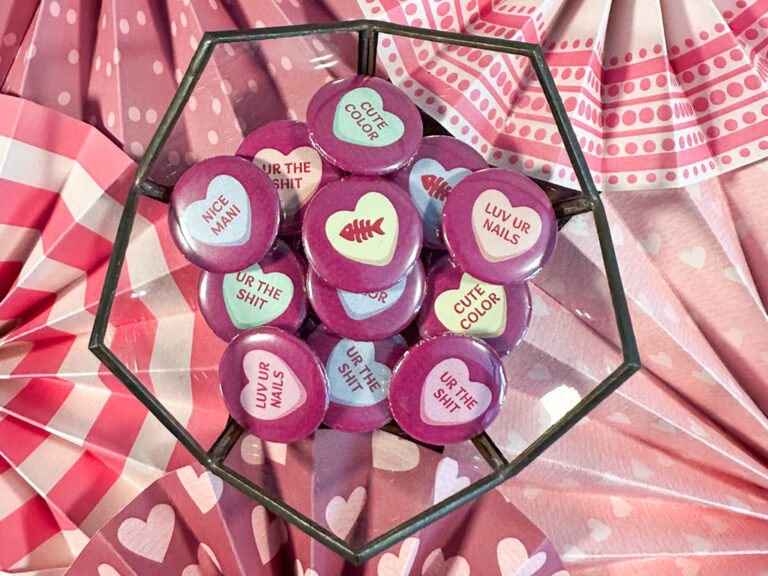 container of valentines day themed pin backed buttons